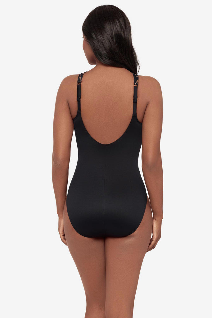 Woman turned away wearing a black and brown printed one-piece swimsuit