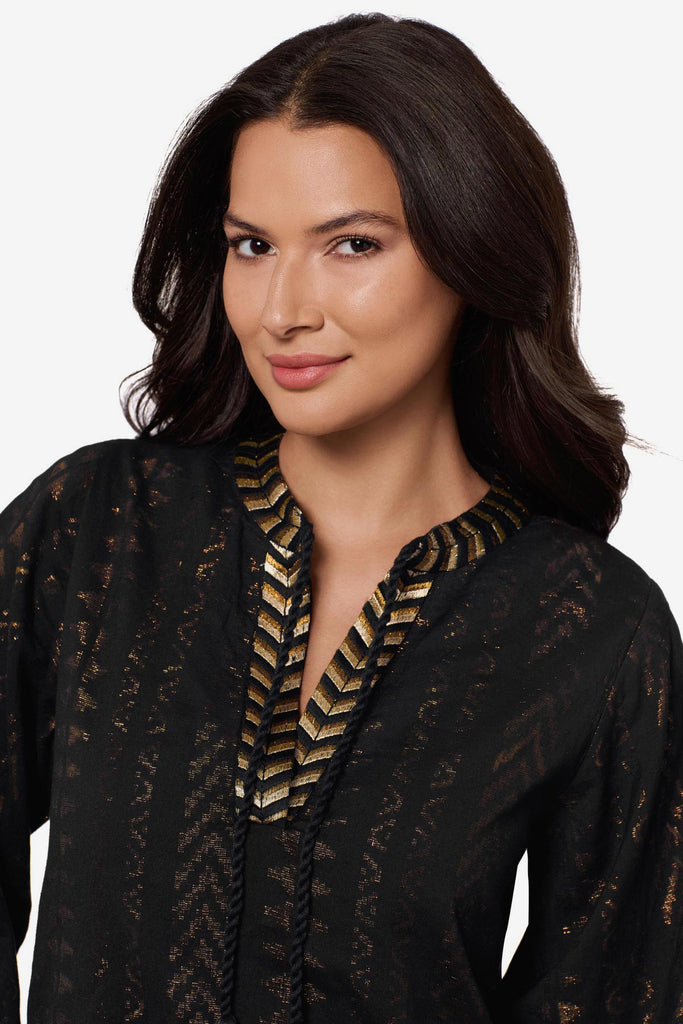 Close up of woman wearing a black pull-over kimono swim dress with gold detailing on the front