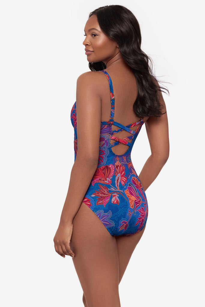 Woman turned left wearing a one-piece swimsuit with a red and orange flower print
