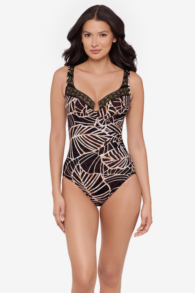 Woman wearing a brown abstract printed one-piece swimsuit with a detailed print on the sweetheart neckline
