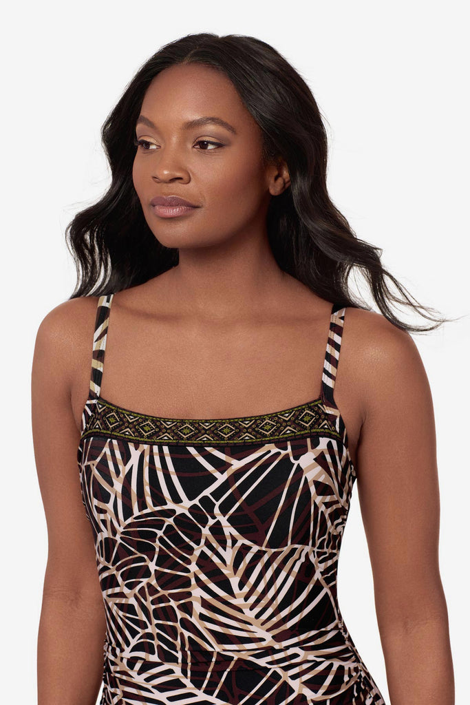 Close up of woman wearing a brown abstract printed one-piece swimsuit with a detailed pattern on the neckline