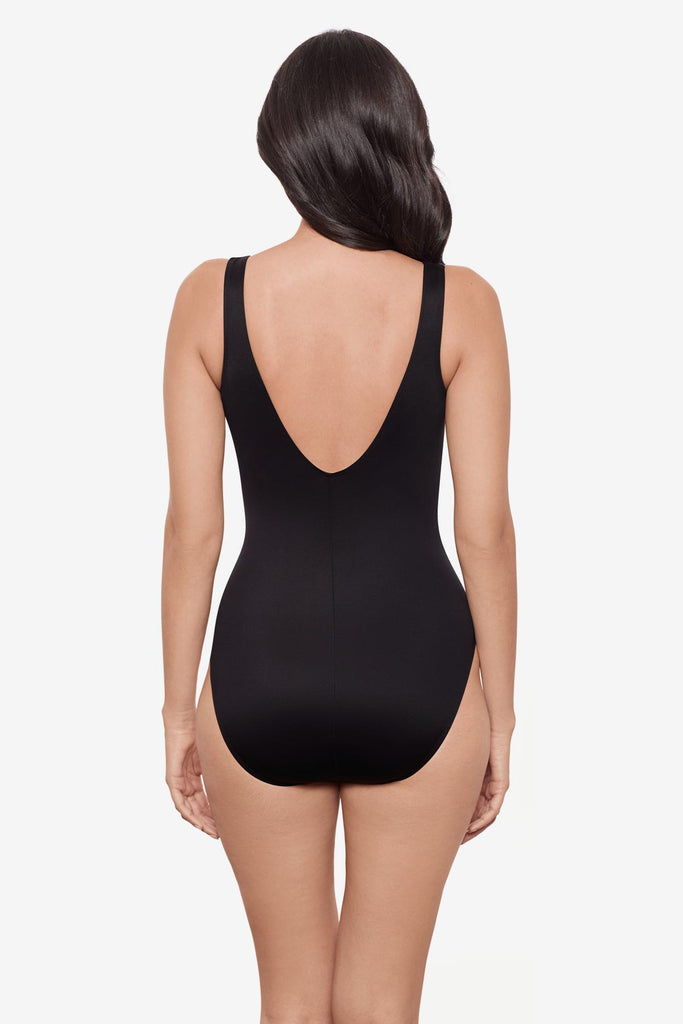 Woman faced away wearing a black and brown printed one-piece swimsuit