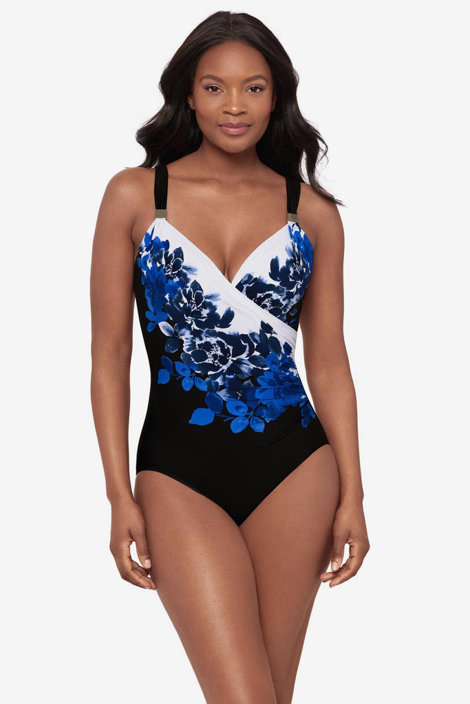 Woman wearing a blue floral printed one-piece swimsuit with silver-tone embellishments on the straps
