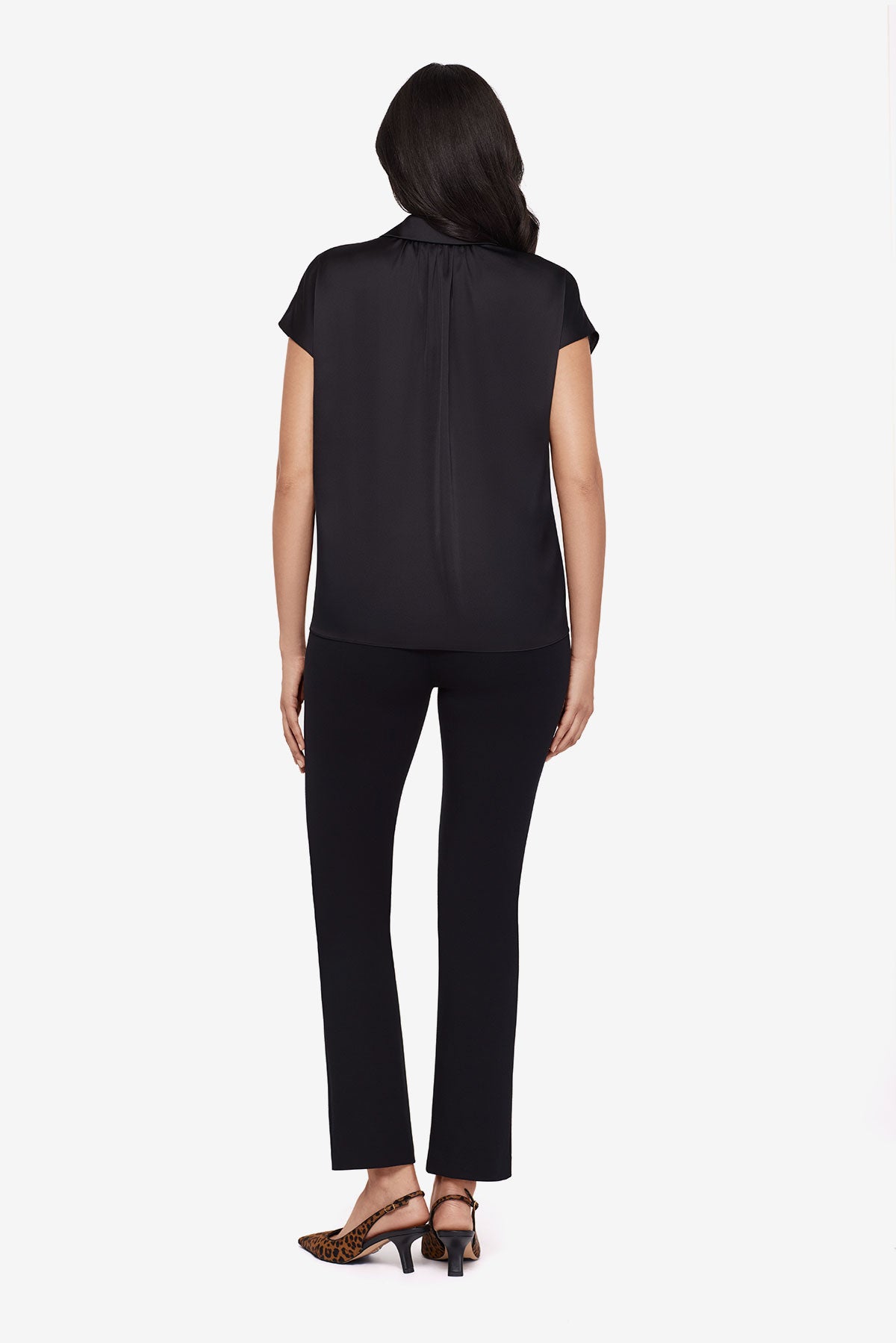 Woman turned away wearing a black button-down blouse with short sleeves with matching black pants