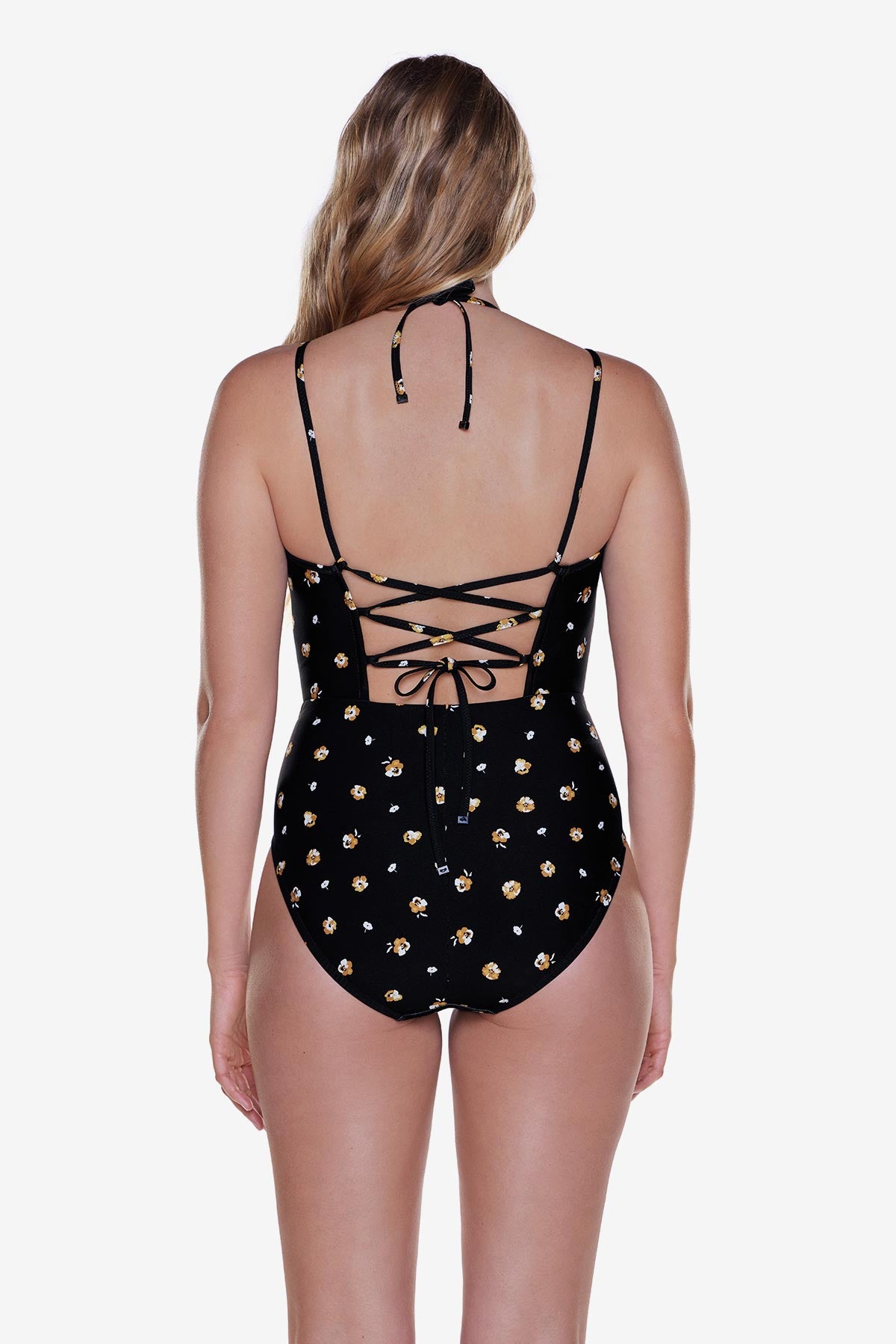 Woman turned away wearing a one-piece swimsuit with a small floral pattern and X tie back