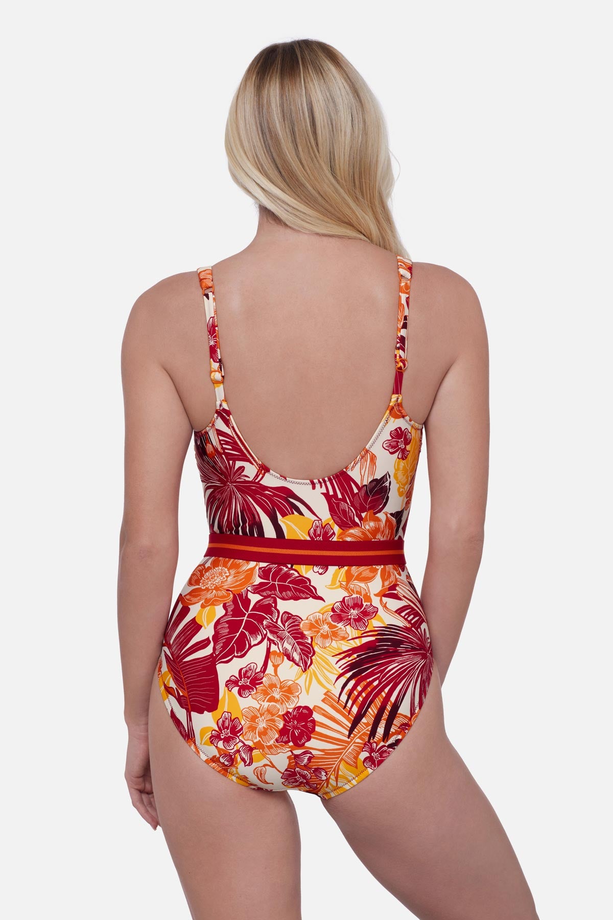 Woman turned away wearing a multicolored palm leaf printed one-piece swimsuit with a belt