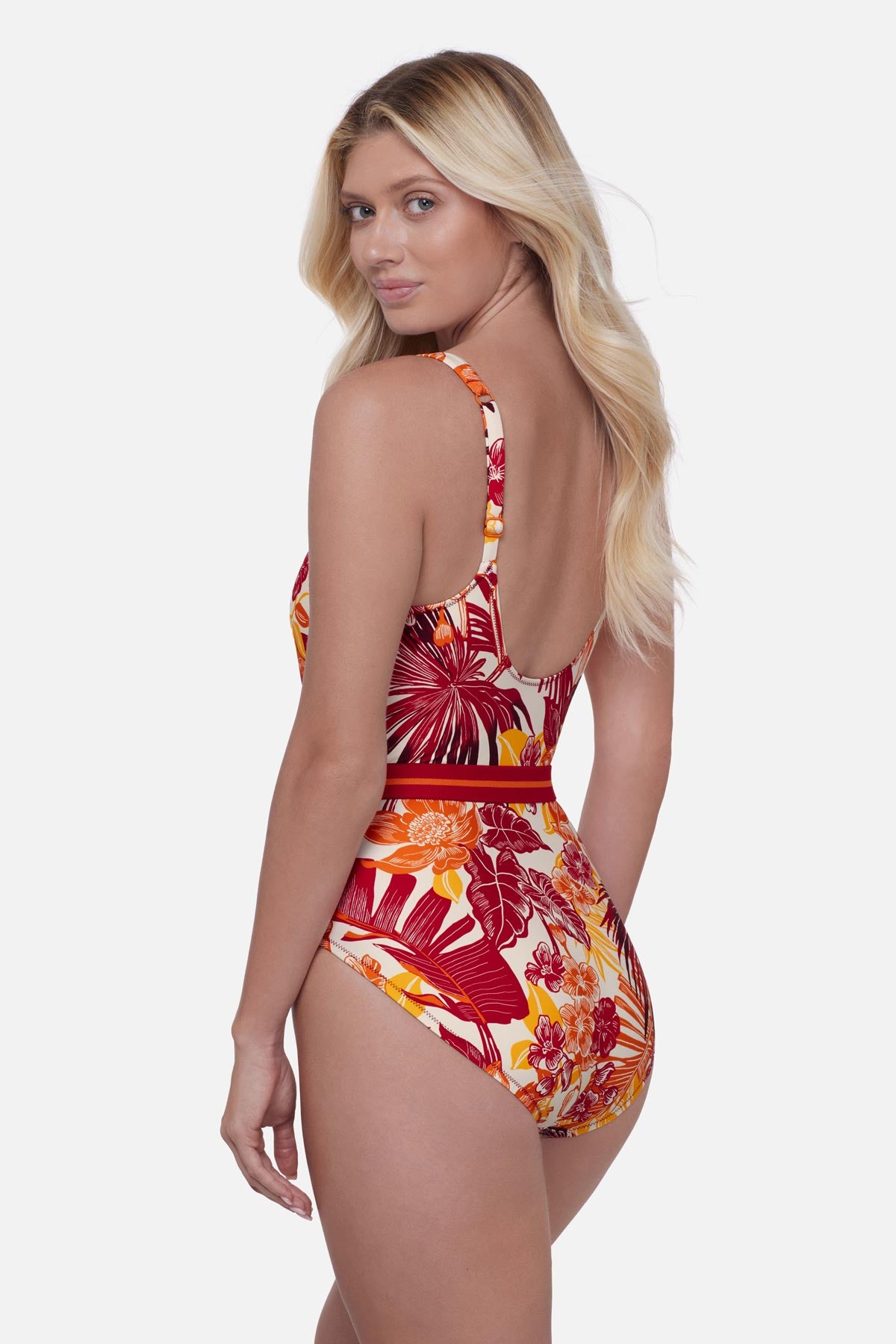 Woman turned left wearing a multicolored palm leaf printed one-piece swimsuit with a belt