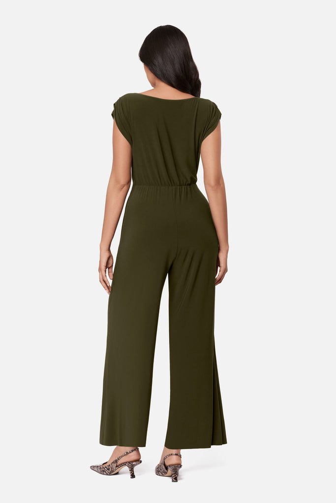 Woman turned away wearing a green romper with a sash around the waist