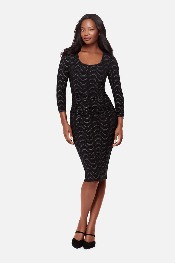 Woman wearing a black long sleeve dress with a glittery wave pattern