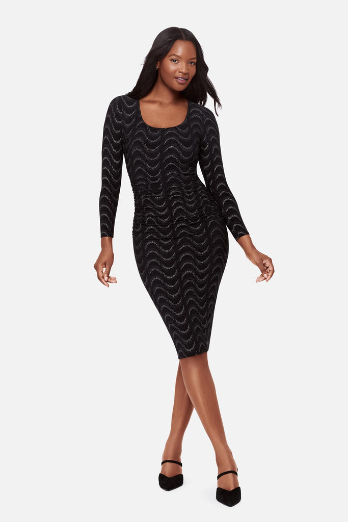 Woman wearing a black long sleeve dress with a glittery wave pattern