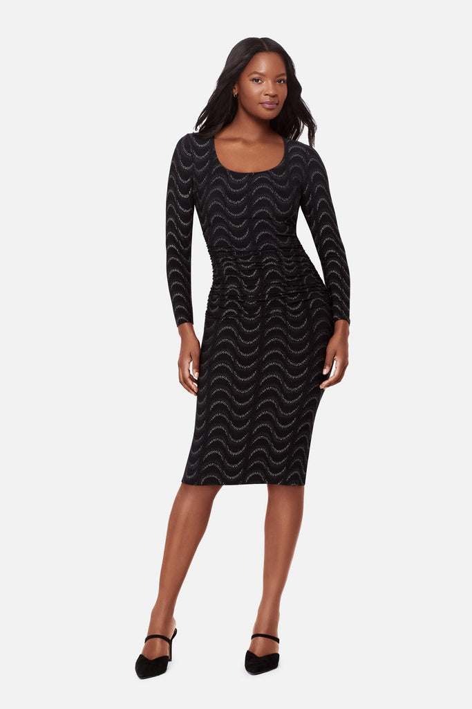 Woman wearing a black long sleeve dress with a glittery wave pattern