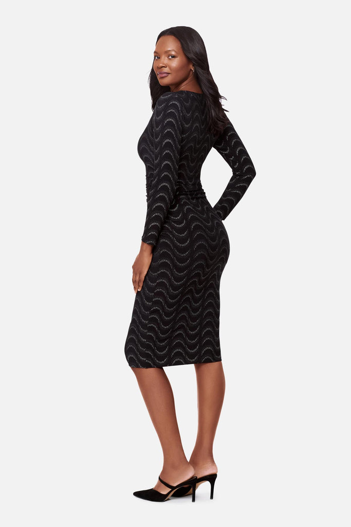 Woman faced left wearing a black long sleeve dress with a glittery wave pattern