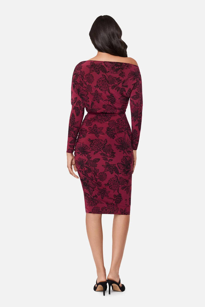 Woman turned away wearing a maroon long sleeve dress with a floral pattern