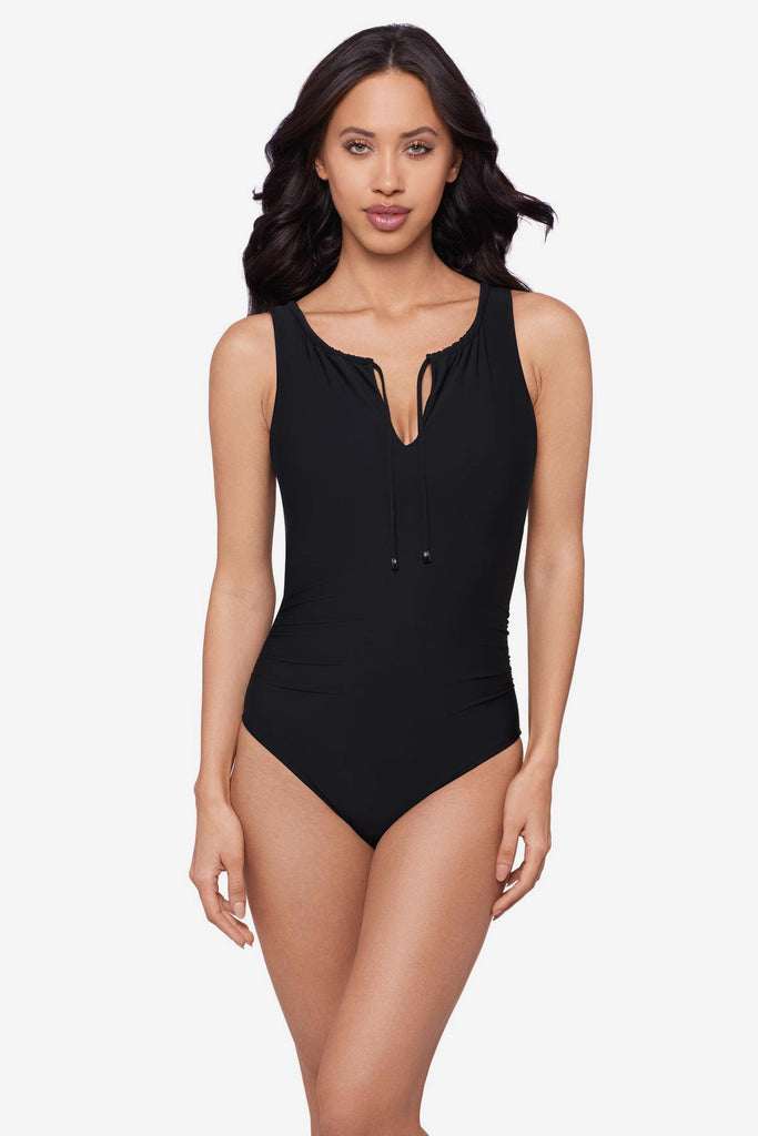 Woman wearing a black one-piece swimsuit with tie detail at the neckline