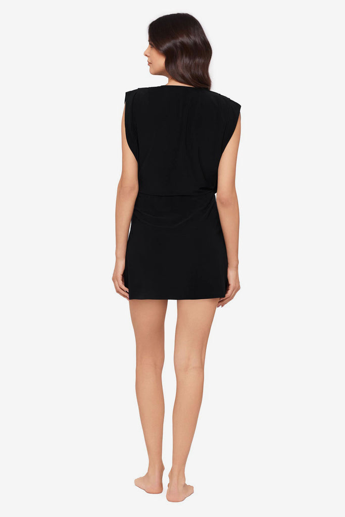 Woman turned away wearing a black swim dress cover up 