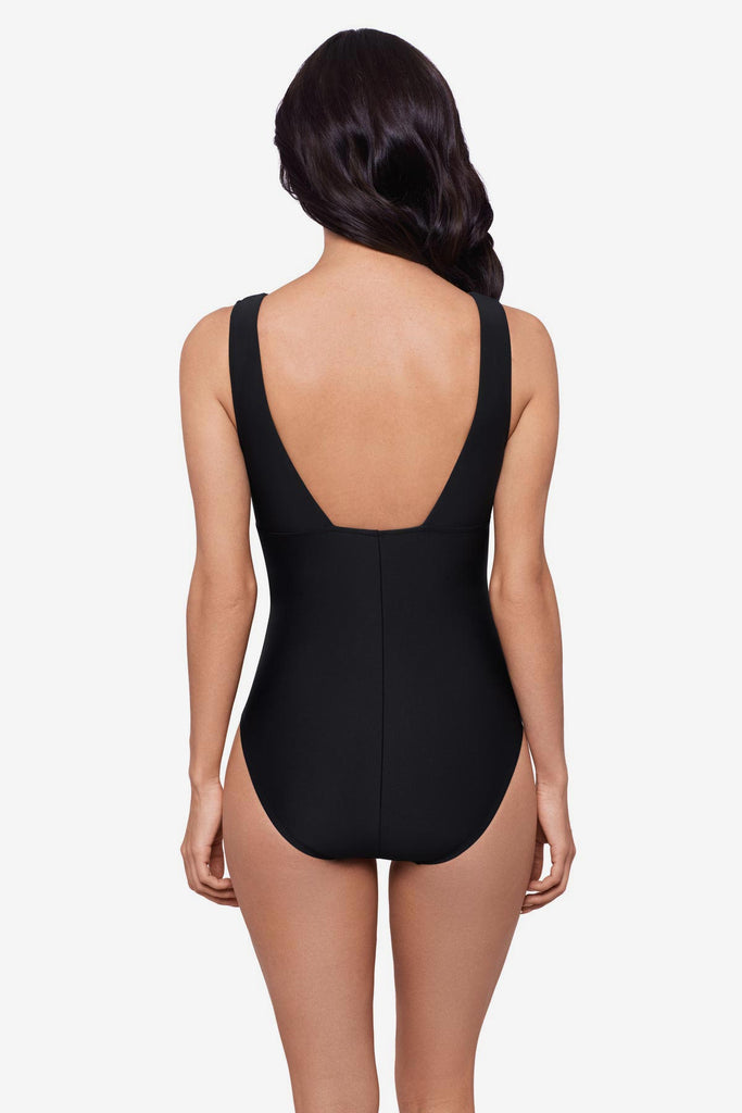 Woman faced away wearing a black one-piece swimsuit 