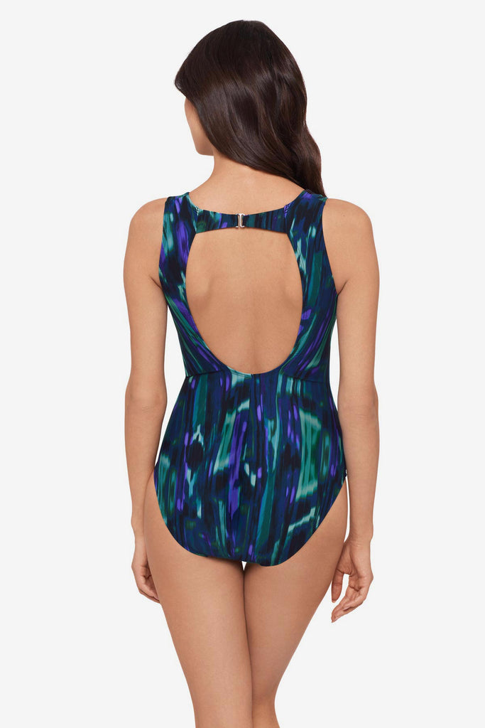 Woman faced away wearing a green tie-dyed one -piece swimsuit with a cutout back