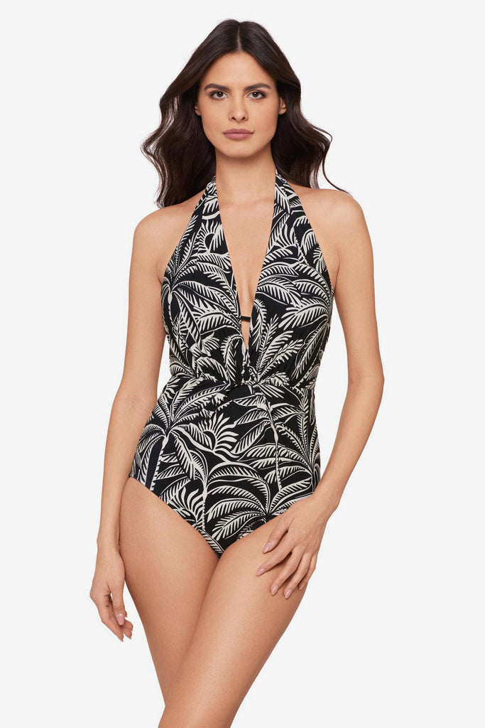 Woman wearing a black and white palm leaf printed one-piece swimsuit with a deep V neckline