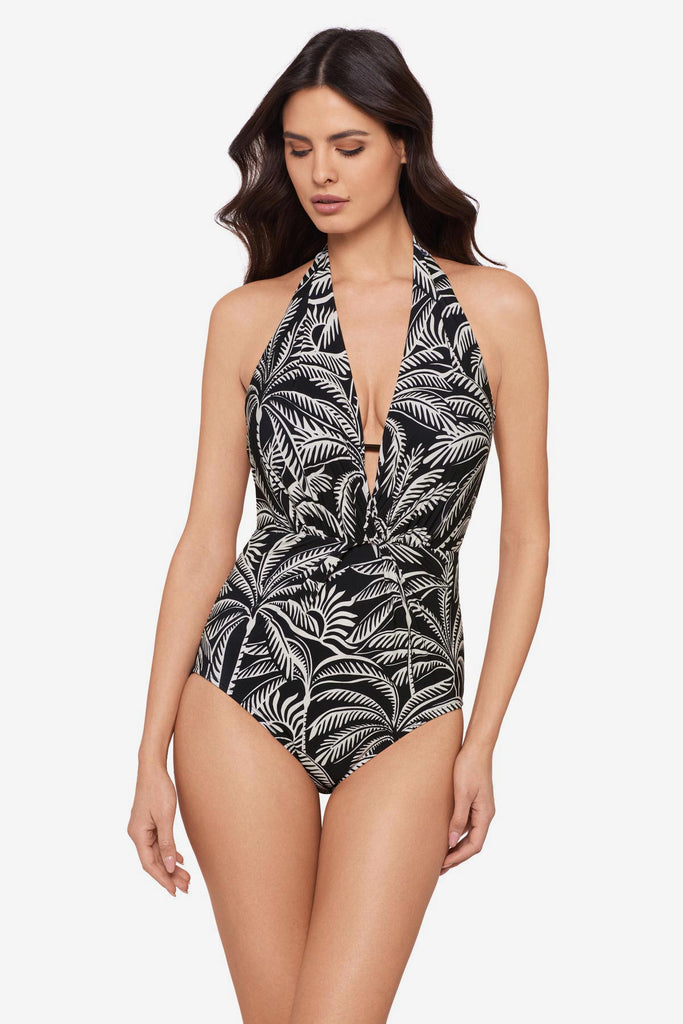 Woman wearing a black and white palm leaf printed one-piece swimsuit with a deep V neckline