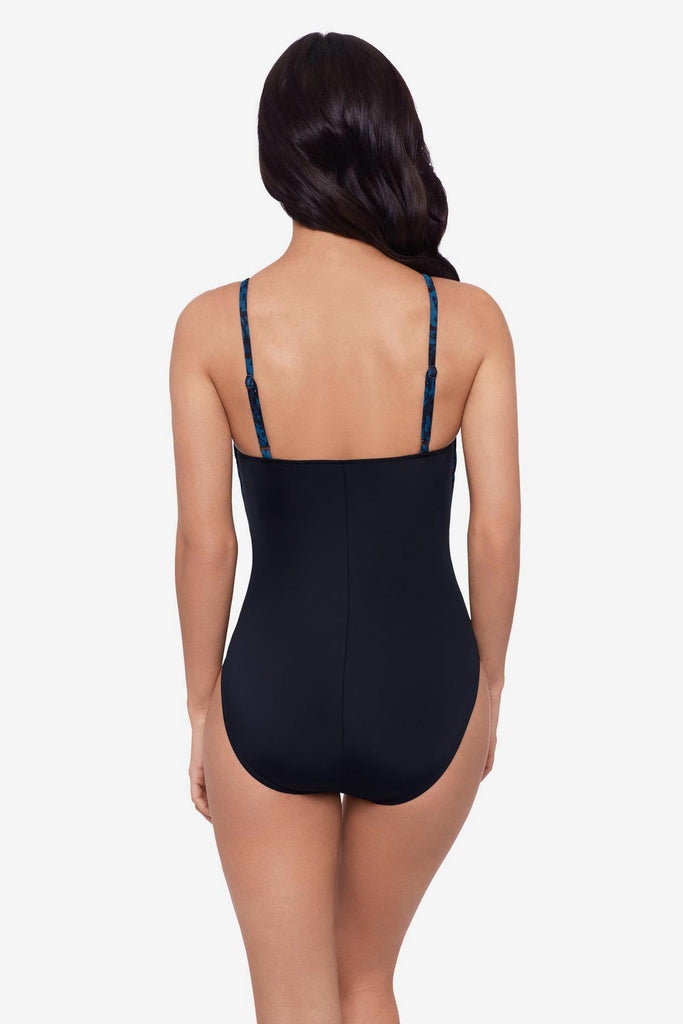 Woman turned away wearing a black and blue printed one-piece swimsuit 