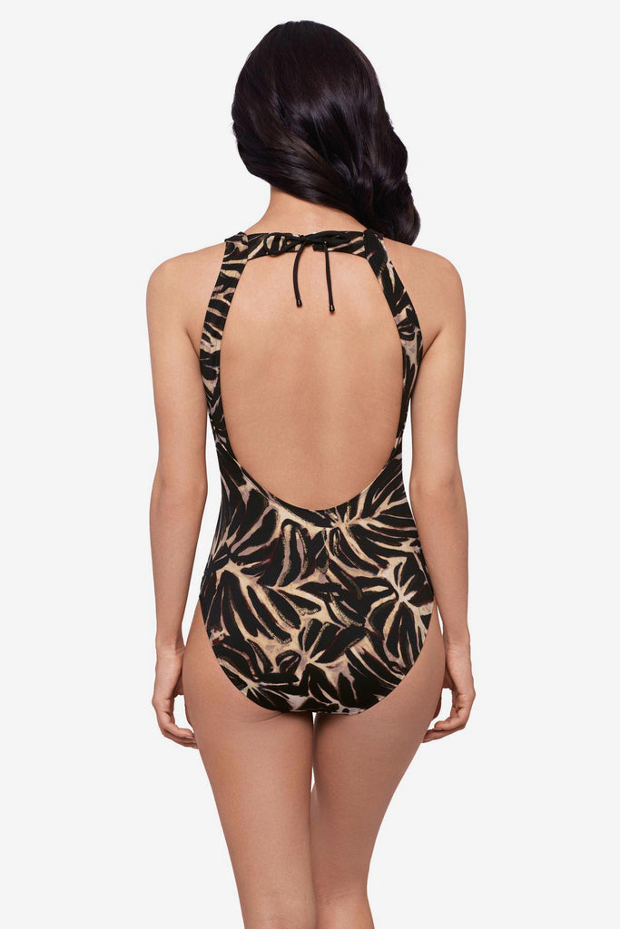 Woman turned away wearing a brown leaf printed one-piece swimsuit 