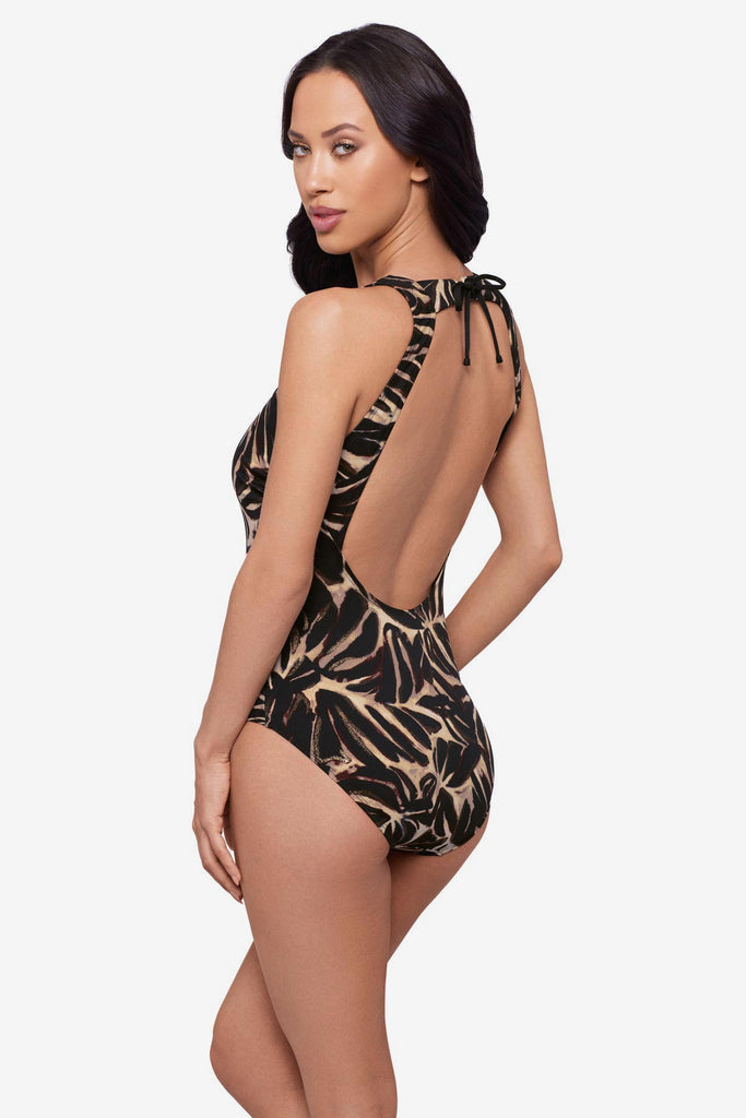 Woman faced left wearing a brown leaf printed one-piece swimsuit